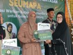 Putri Misinaldila menerima hadiah juara 2 Kompetisi Seumapa yang diserahkan oleh Penyair Wanita Aceh, Rosni Idham, Ahad 17 Mei 2026. (BASAJAN.NETHARIS MUNAWAR)