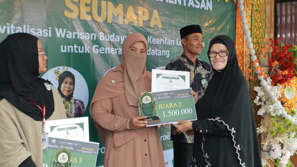 Putri Misinaldila menerima hadiah juara 2 Kompetisi Seumapa yang diserahkan oleh Penyair Wanita Aceh, Rosni Idham, Ahad 17 Mei 2026. (BASAJAN.NETHARIS MUNAWAR)
